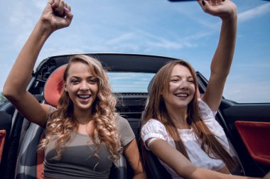 üstü açık bir araba ön koltukta oturan iki genç kadın