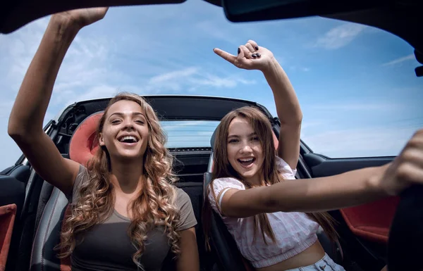 Duas namoradas desfrutando de uma viagem em um carro conversível — Fotografia de Stock