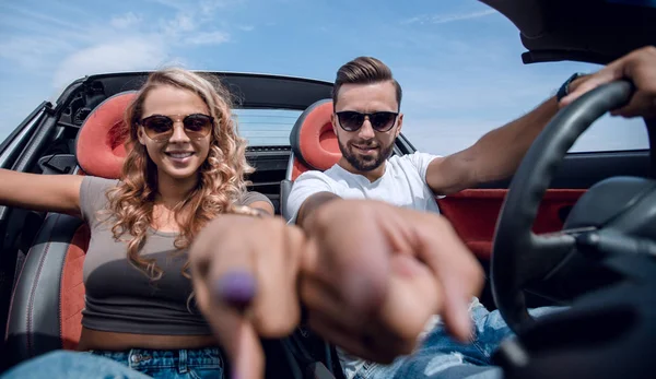 Aus nächster Nähe. Glückliches Paar sitzt im Auto und zeigt auf dich. — Stockfoto