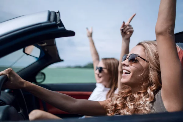 Jovens mulheres felizes dirigindo em carro cabriolet e rindo — Fotografia de Stock