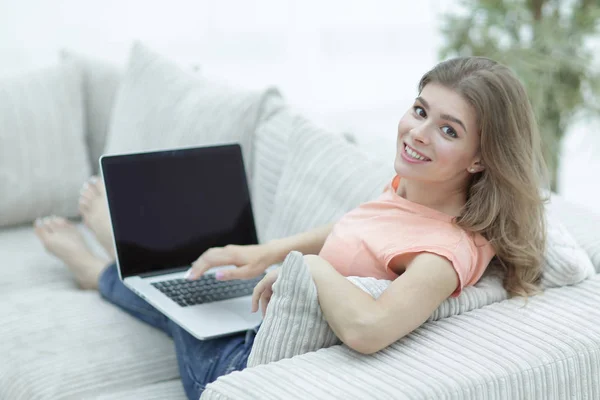 Ung kvinna som arbetar med laptop sitter i vardagsrummet — Stockfoto
