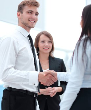 onun ortağı ile tokalaşırken komik gülümseyen iş adamı.