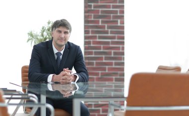 Bir boş konferans salonunda bir masada oturan proje yöneticisi