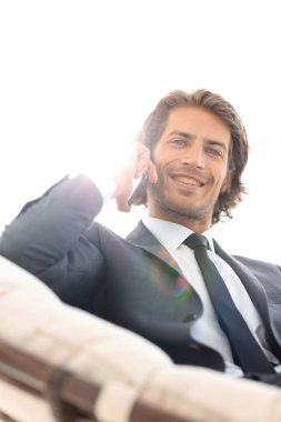 iş adamı rahat bir sandalyede otururken Smartphone'da konuşuyor.