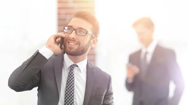 Confident young man talking on phone in office — Stock Photo, Image