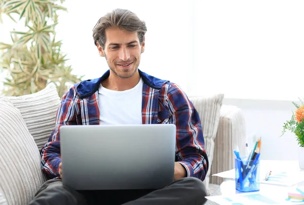 Glücklicher Sieger. Junger aufgeregter Mann sitzt mit Laptop auf Sofa. — Stockfoto