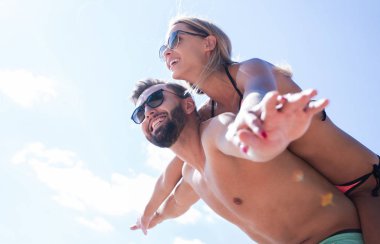 Kumsalda kadını sırtında taşıyan bir adam..