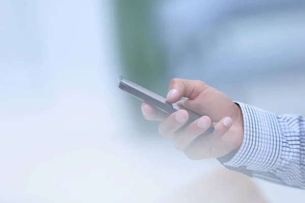 Primer plano. Un hombre sostiene un teléfono inteligente . — Foto de Stock