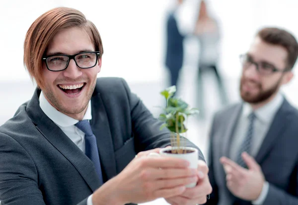 Joven hombre de negocios le muestra un brote joven — Foto de Stock