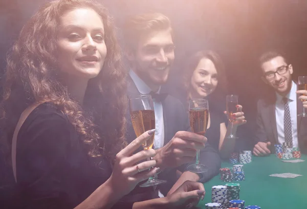 Grupo de amigos sentados en la mesa de juego en el casino — Foto de Stock