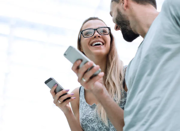 Feliz pareja joven con teléfonos inteligentes discutir archivos de vídeo — Foto de Stock