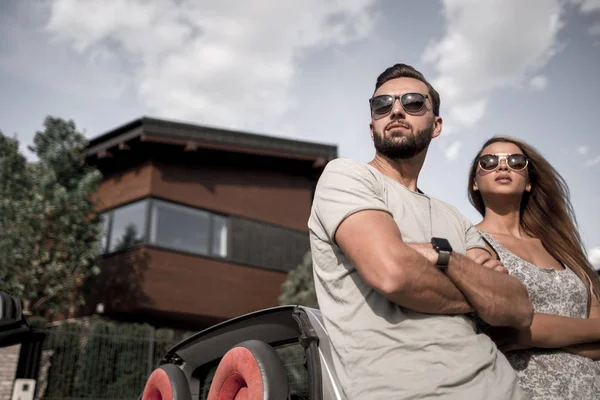 Beautiful couple standing near a convertible car — Stock Photo, Image