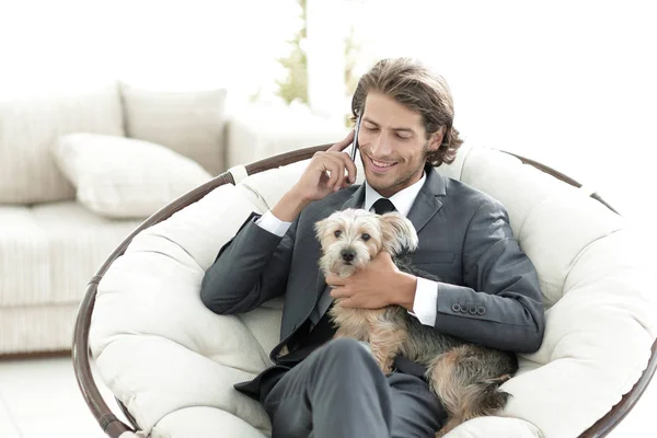 Hombre de negocios está sosteniendo a su mascota y hablando en un smartphone —  Fotos de Stock