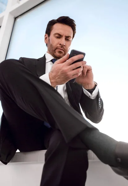 Businessman typing SMS on his smartphone Stock Image