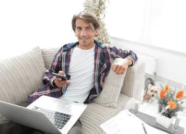 dizüstü bilgisayar ve oturma odasında kanepede oturan smartphone başarılı adam