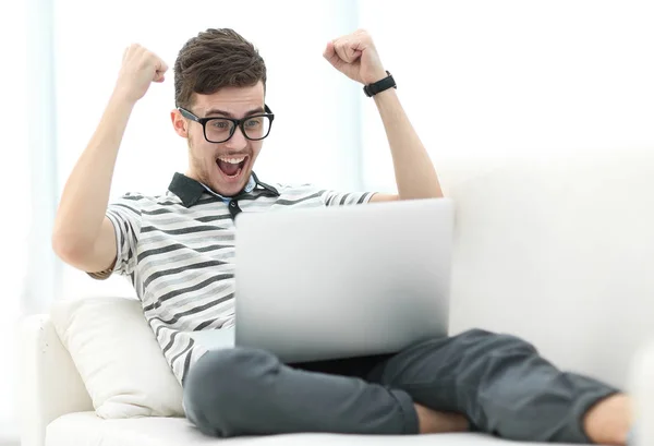 Hombre feliz con el ordenador portátil sentado en el sofá — Foto de Stock