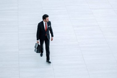 Uzaklara. Deri çantalı bir iş adamı geliyor.