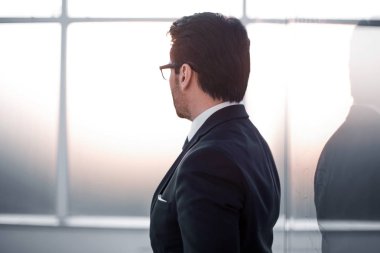 yan görünümü. ofis pencere duran işadamı.