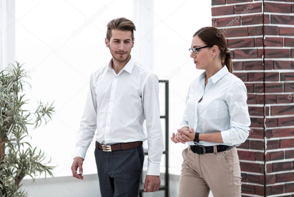 Manager and the employee are on the office corridor