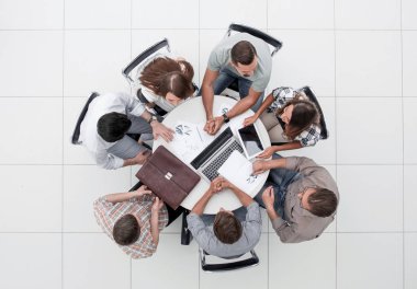 Üst görüş. İş ekibi yuvarlak bir masa tutuyor.