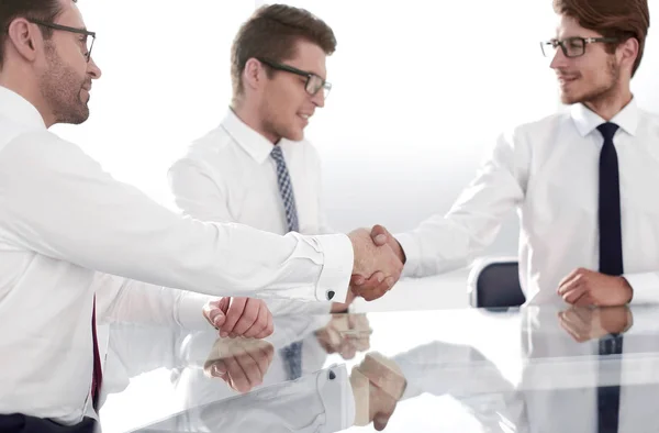 Affärspartners skakar hand när de sitter vid bordet. — Stockfoto