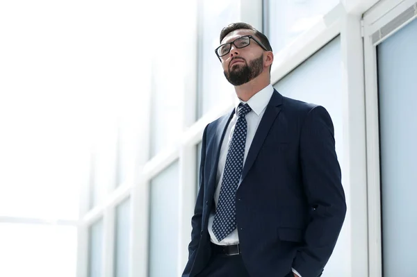 Serious businessman standing in a spacious office — Stock Photo, Image