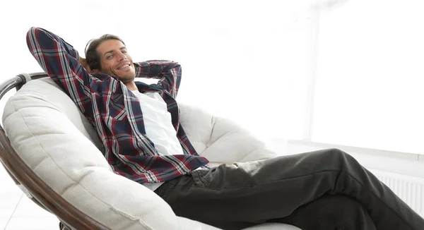 Cara moderno está descansando sentado em uma grande cadeira confortável. vista lateral . — Fotografia de Stock