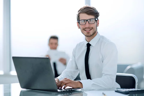 Joven empresario exitoso escribiendo en el ordenador portátil en el lugar de trabajo —  Fotos de Stock