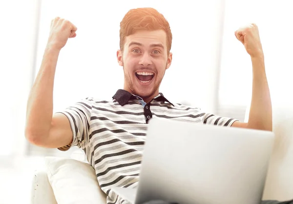 Hombre feliz con el ordenador portátil sentado en el sofá — Foto de Stock