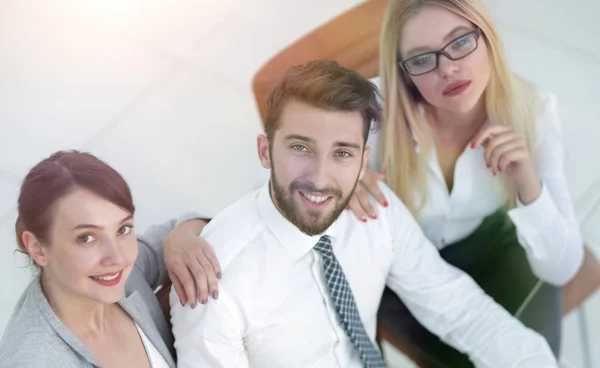 Exitoso equipo de negocios sentado en la mesa y mirando a la cámara . — Foto de Stock