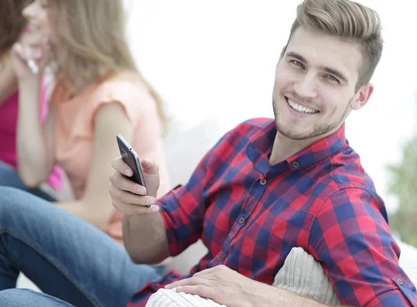 Современный парень со смартфоном и его друзья, сидящие на диване — стоковое фото