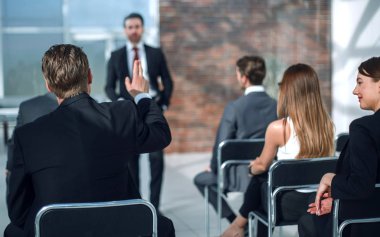 personel toplantısında bir soruyu cevaplamak için bir el yükseltir