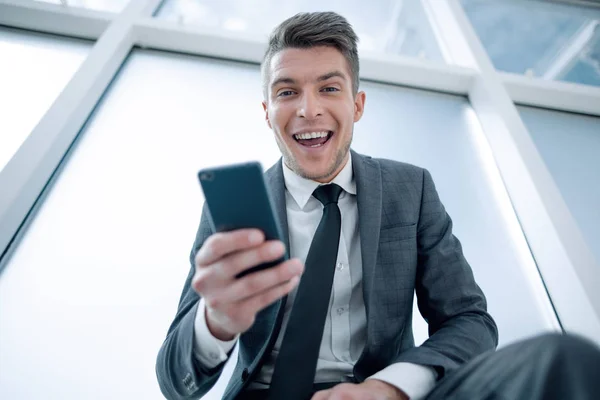 Glad affärsman med telefon tittar på kameran — Stockfoto