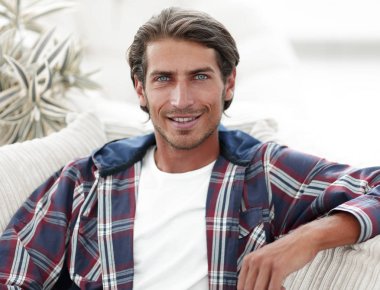 dizüstü bilgisayarda çalışan ve kameraya bakarak bir genç adam. Yukarıdan görüntülemek