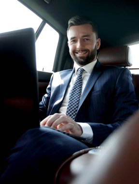 Arabada otururken diz üstü üzerinde çalışan iş adamı