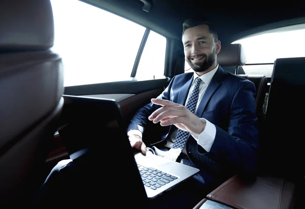 Podnikatel, sedí na zadním sedadle v autě a ukazoval prstem vpřed — Stock fotografie