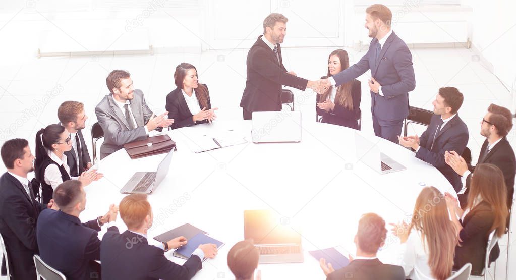 business partners shake hands at the talks near the round table