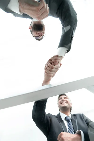 View from below. From behind the glass. Handshake of business partners