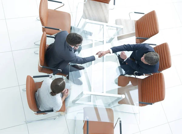 Um aperto de mão na mesa. Reunião em torno de uma mesa de reuniões. — Fotografia de Stock