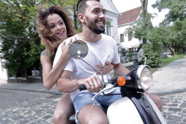 Şık genç çift bir scooter sokakta oturuyor..