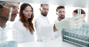 arka plan görüntüsü sıvı cam tüp içinde eğitim microbiologists oluşan bir gruptur.