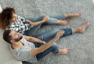 yeni bir oturma odasında bir halı üzerinde oturan yeni evli çift