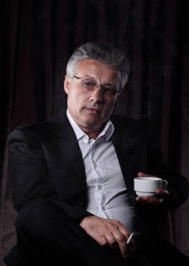 bir sigara ve bir fincan kahve tutan işadamı