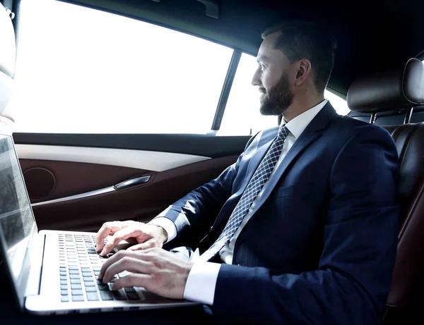 Uomo d'affari digitando testo sul computer portatile mentre seduto in auto — Foto Stock