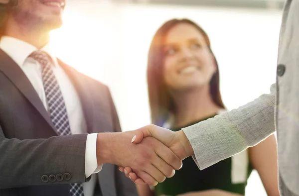 Empresarios estrechando la mano contra la habitación con grandes ventanales — Foto de Stock