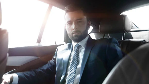 Businessman sitting in the back seat of a car — Stock Photo, Image
