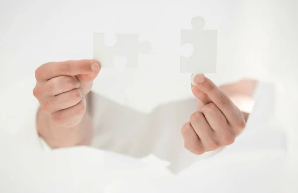 Man connecting pieces of puzzles, breaking the wall of paper. — Stock Photo, Image