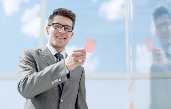 Dipendente sorridente leggere un adesivo nota sul vetro — Foto Stock