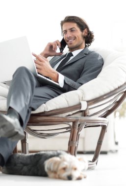 onun evinde sandalyede oturan smartphone cep telefonu ile konuşurken işadamı