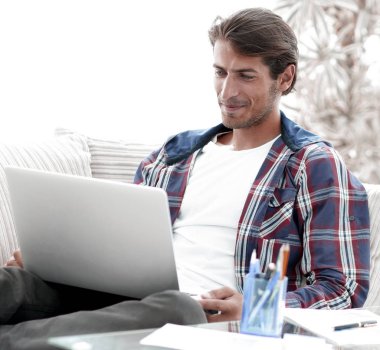 mutlu genç adam evden dizüstü bilgisayar ile çalışma.